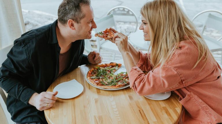 A couple sharing a pizza at a table.