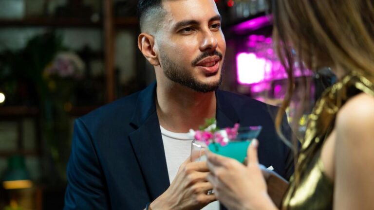 A man in a blue blazer talking to a woman inside a bar.