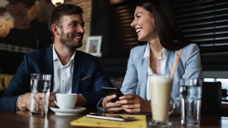 A man smiling warmly at someone across a café, keeping body language relaxed