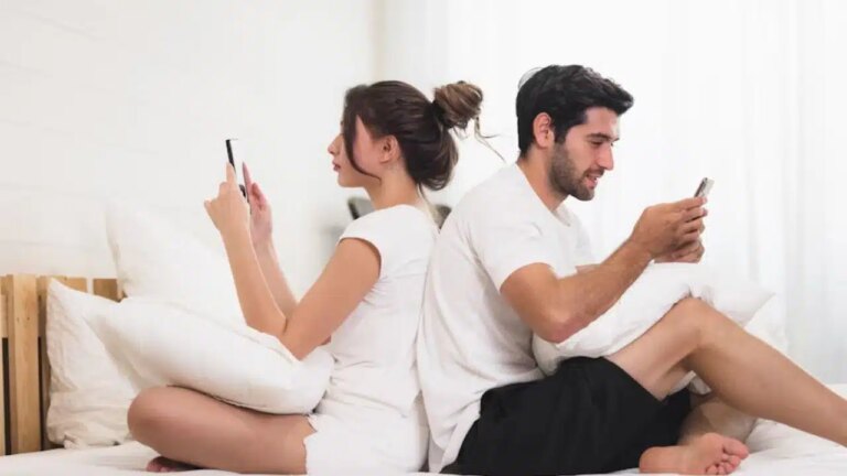 Emotionally distant couple sitting together but disengaged