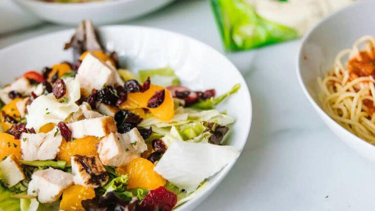 A bowl of salad with grilled chicken, mandarin oranges, dried cranberries, and mixed greens.