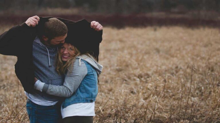 A couple cuddling on a field.